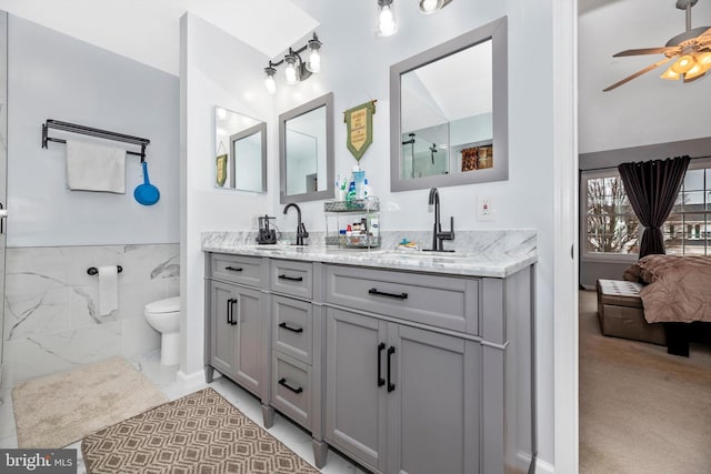 bathroom featuring double vanity, a ceiling fan, tile walls, and a sink