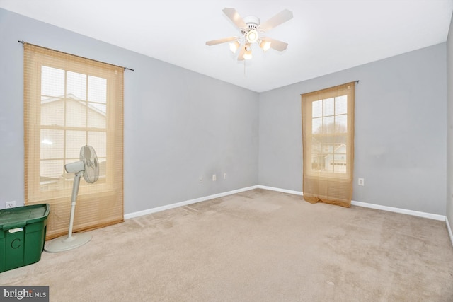 unfurnished room featuring a ceiling fan, light colored carpet, and baseboards