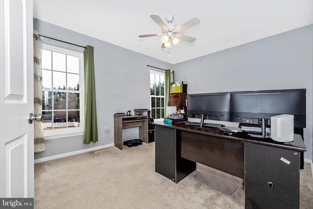 office space featuring light carpet, baseboards, and a ceiling fan