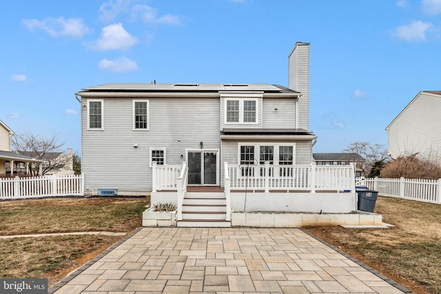 back of house with a deck, solar panels, a yard, and a fenced backyard