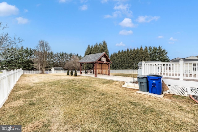 view of yard with a fenced backyard, a deck, a gazebo, and a storage unit