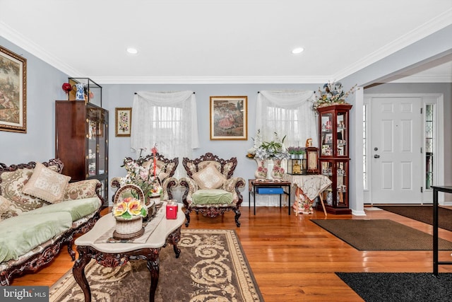 living area with baseboards, recessed lighting, wood finished floors, and crown molding