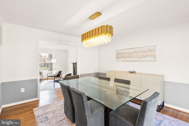 dining space with crown molding, baseboards, wood finished floors, and a notable chandelier