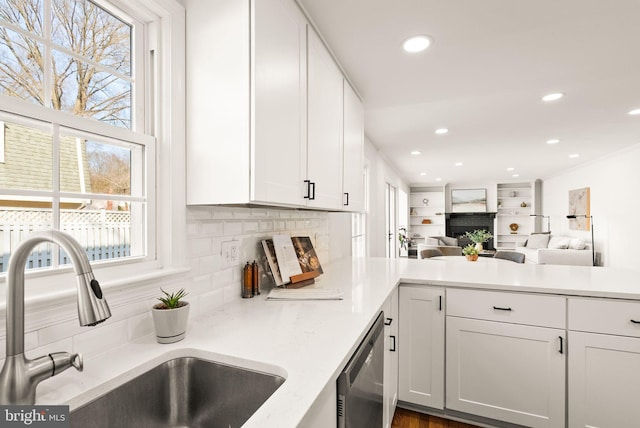 kitchen featuring a sink, white cabinetry, open floor plan, decorative backsplash, and dishwasher