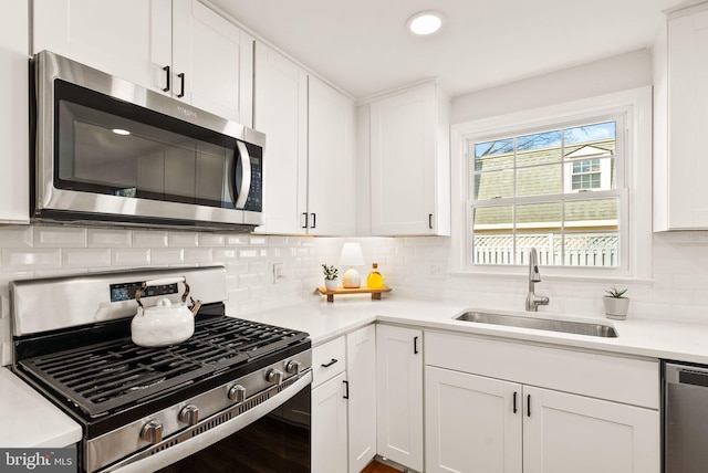 kitchen with white cabinetry, stainless steel appliances, a sink, and light countertops