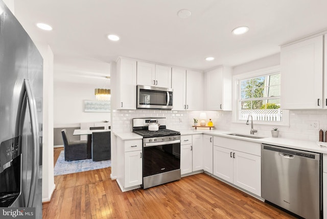 kitchen featuring a sink, white cabinetry, light wood-style floors, light countertops, and appliances with stainless steel finishes