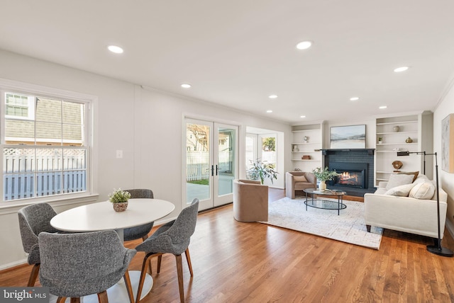 dining space with french doors, recessed lighting, light wood-type flooring, and a brick fireplace