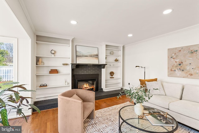 living area with a fireplace, ornamental molding, wood finished floors, and recessed lighting