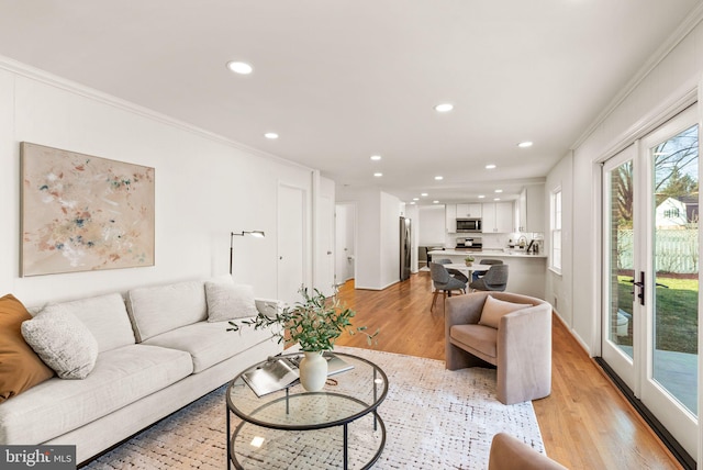 living room with light wood-style flooring, ornamental molding, and recessed lighting