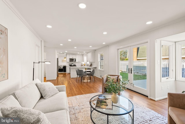 living area featuring ornamental molding, recessed lighting, french doors, and light wood finished floors