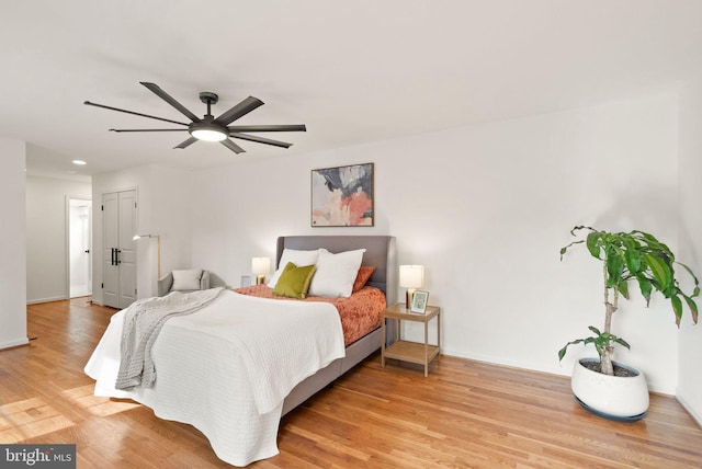 bedroom with light wood-style floors, ceiling fan, and baseboards