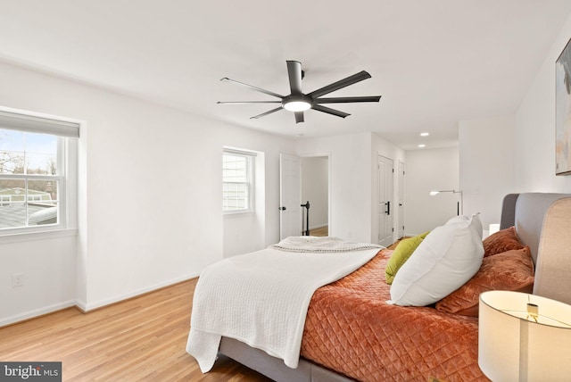 bedroom with baseboards, multiple windows, a ceiling fan, and light wood-style floors