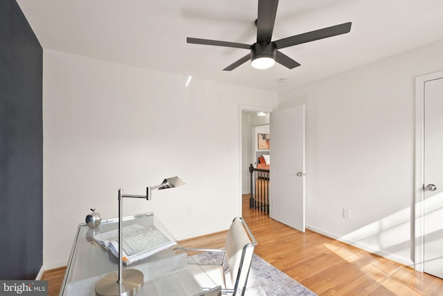 home office with a ceiling fan, baseboards, and wood finished floors