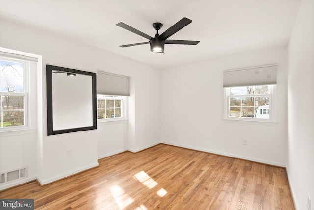 spare room with visible vents, wood finished floors, and a wealth of natural light