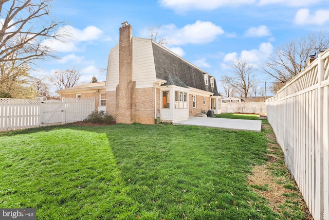 view of home's exterior with brick siding, a patio, a gambrel roof, a gate, and a fenced backyard