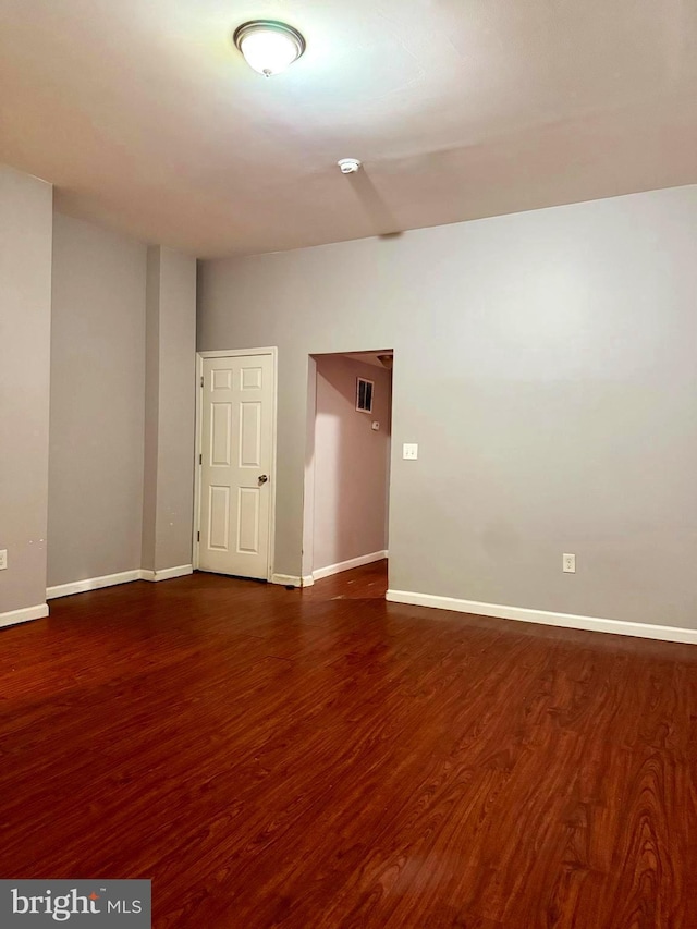 unfurnished room with baseboards and dark wood-type flooring