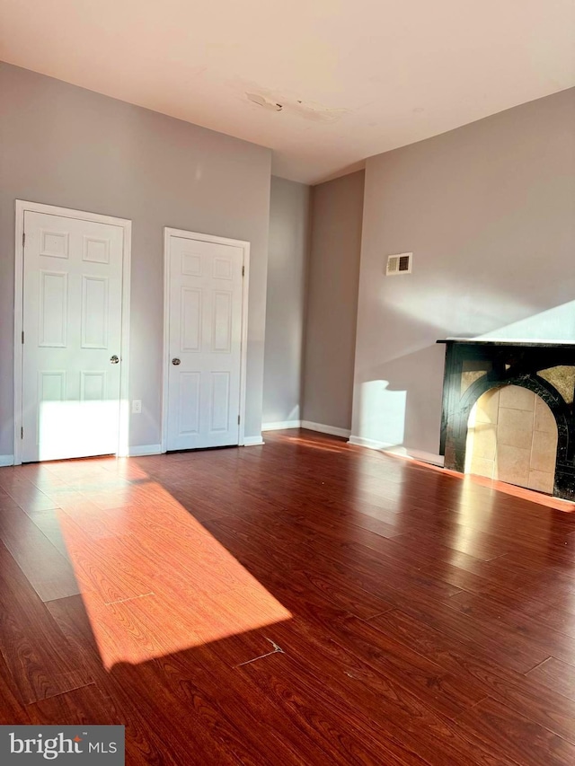 unfurnished living room with baseboards, a fireplace, and wood finished floors