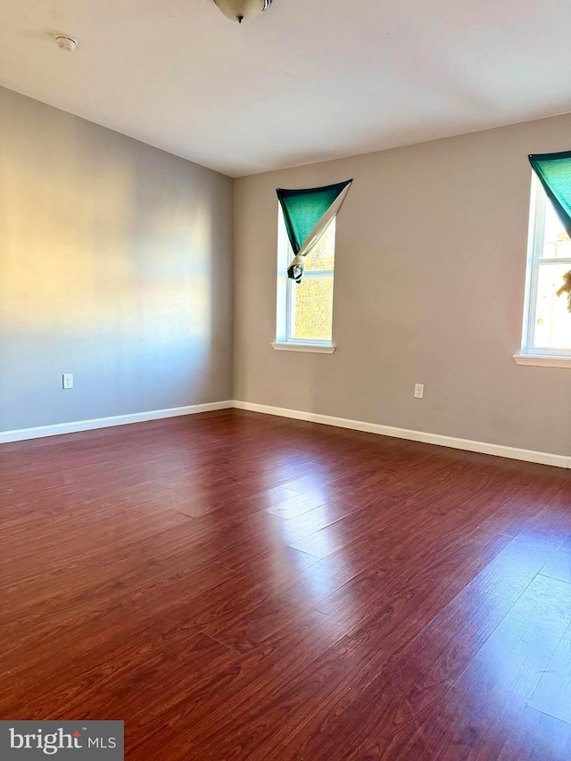 spare room featuring baseboards and dark wood-style floors