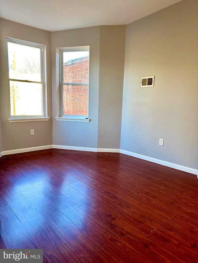 empty room featuring baseboards, visible vents, and wood finished floors