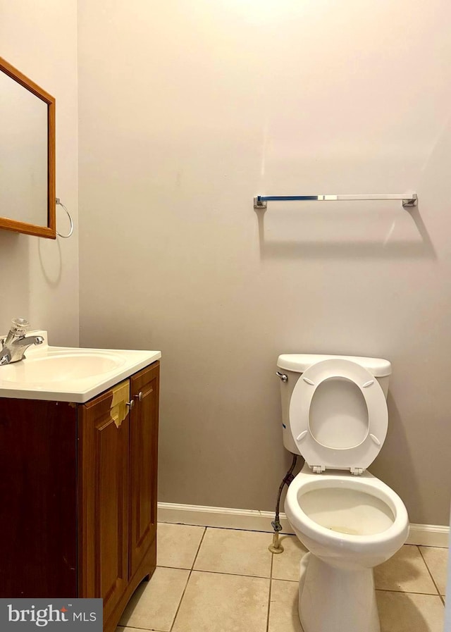 half bath with baseboards, toilet, tile patterned flooring, and vanity