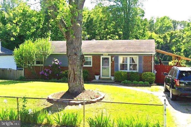 single story home with brick siding, a front lawn, and a fenced front yard