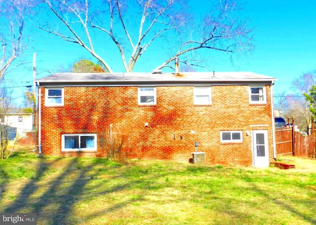 rear view of house featuring a yard, brick siding, fence, and central air condition unit