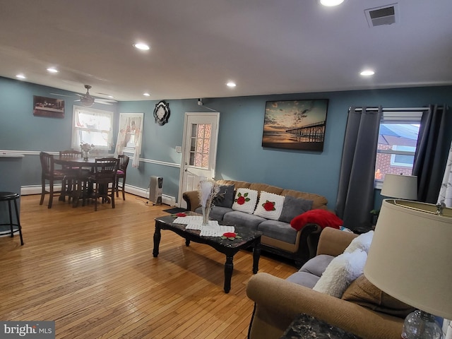 living area with a baseboard radiator, wood-type flooring, a wealth of natural light, and recessed lighting