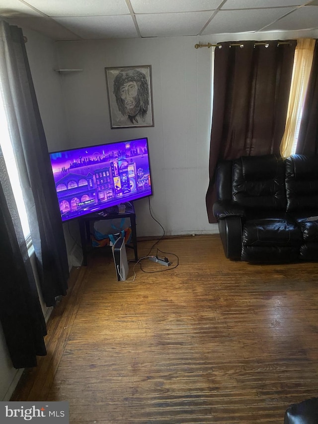 living area with a drop ceiling and wood finished floors