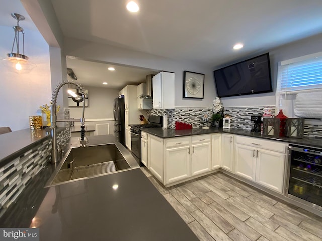 kitchen featuring dark countertops, wine cooler, black appliances, white cabinetry, and pendant lighting