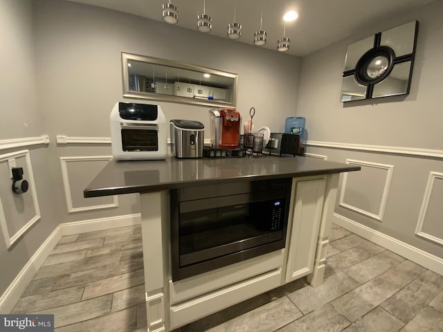 kitchen with dark countertops, a breakfast bar, a center island, built in microwave, and a decorative wall