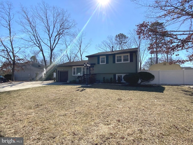 tri-level home featuring a garage, concrete driveway, and fence