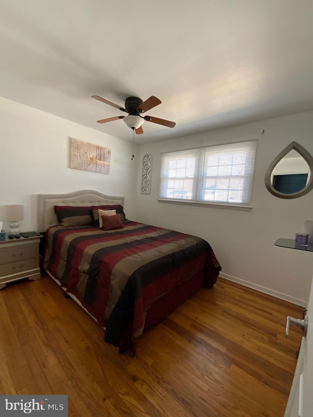 bedroom featuring ceiling fan, baseboards, and wood finished floors