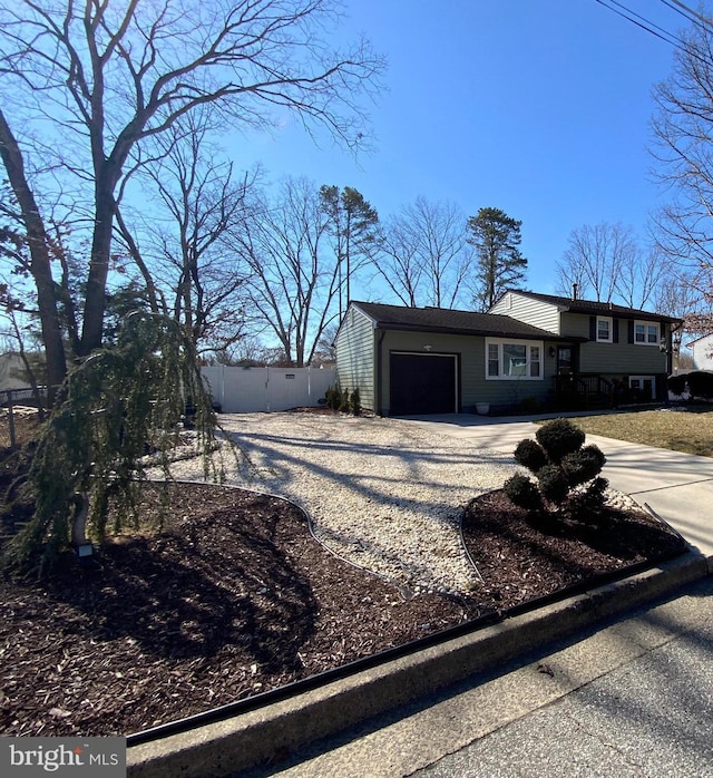 view of front of home with a garage, driveway, and fence