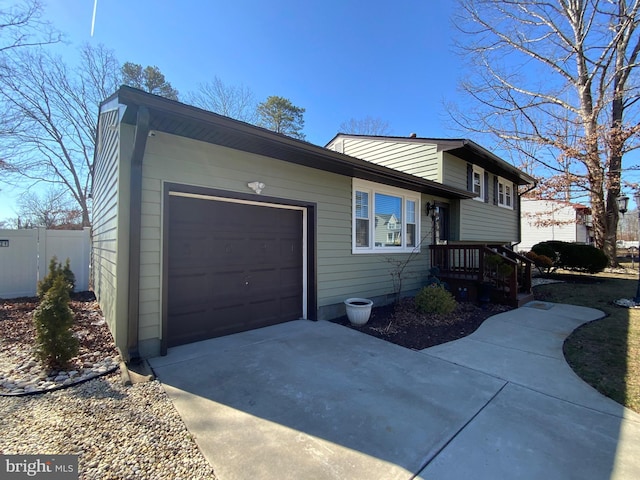 tri-level home featuring a garage, fence, and concrete driveway