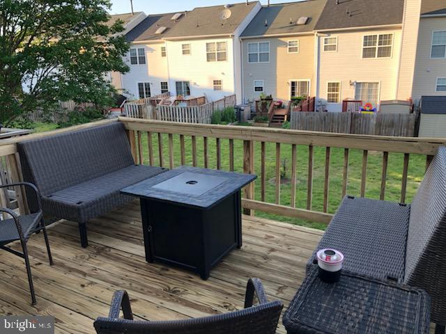 wooden deck featuring an outdoor living space with a fire pit, fence, and a lawn