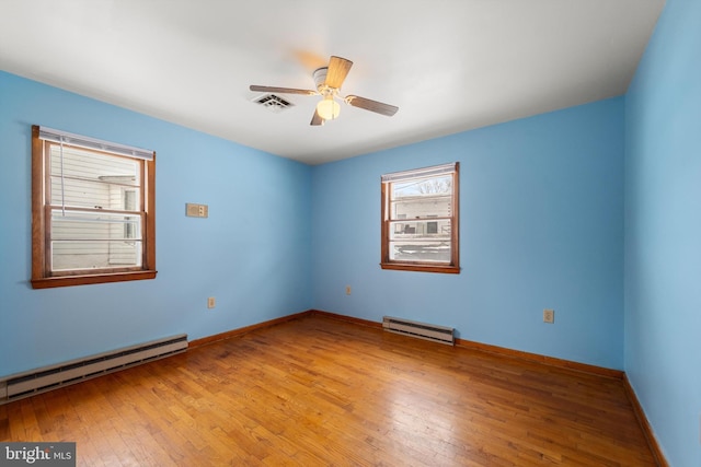 empty room with light wood-style floors, visible vents, a baseboard heating unit, and ceiling fan