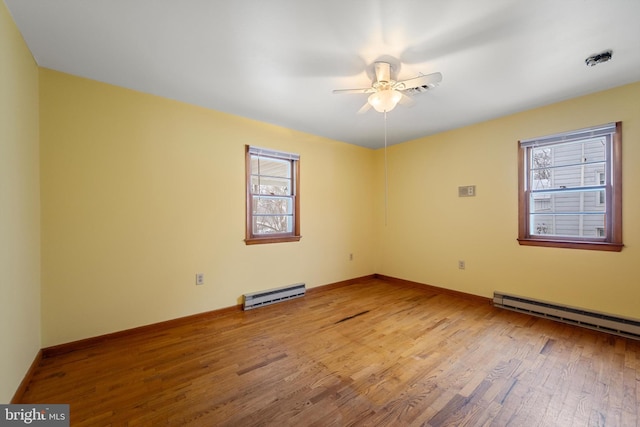 unfurnished room featuring ceiling fan, baseboards, baseboard heating, and wood finished floors