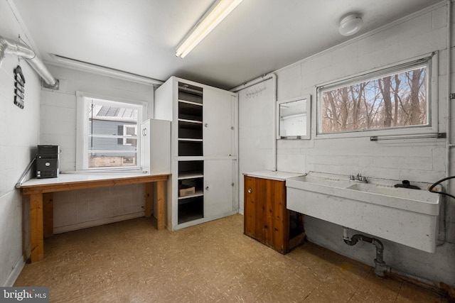 office area with concrete block wall, light floors, and plenty of natural light