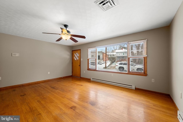 empty room with visible vents, baseboards, ceiling fan, light wood-type flooring, and a baseboard heating unit