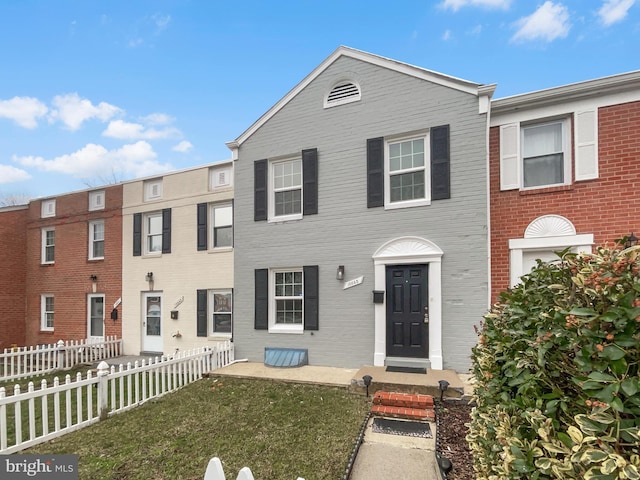 multi unit property featuring fence private yard, brick siding, and a front yard