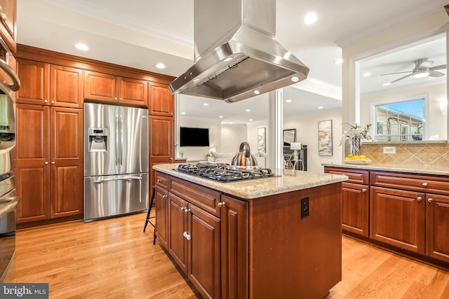 kitchen with island exhaust hood, light stone counters, a kitchen island, crown molding, and stainless steel appliances