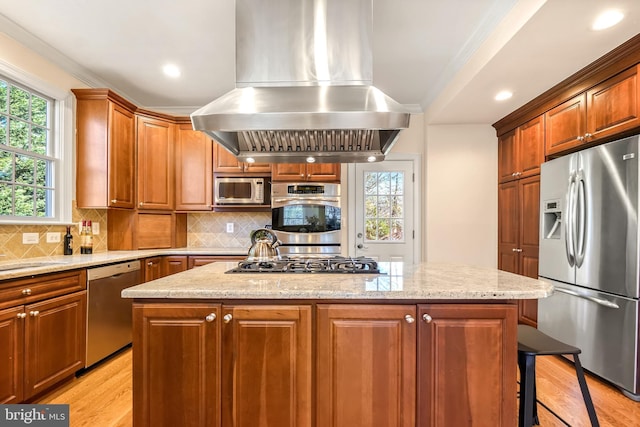 kitchen featuring light hardwood / wood-style flooring, a kitchen island, light stone countertops, appliances with stainless steel finishes, and island range hood