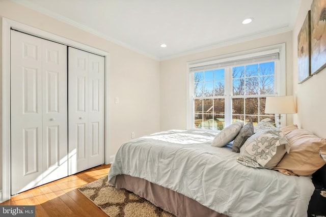 bedroom with light hardwood / wood-style floors, a closet, and ornamental molding