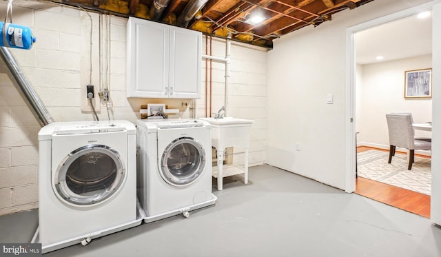 clothes washing area featuring independent washer and dryer and cabinets