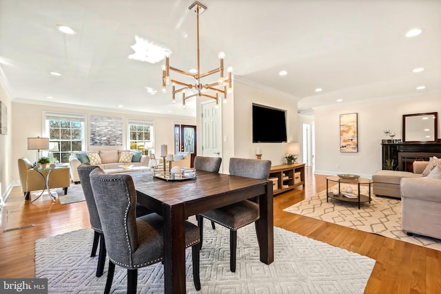 dining room with crown molding, an inviting chandelier, and light hardwood / wood-style floors