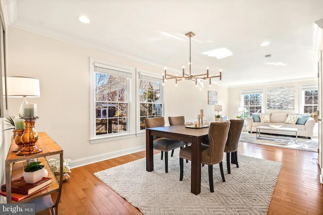 dining room with a notable chandelier, light wood-type flooring, and ornamental molding