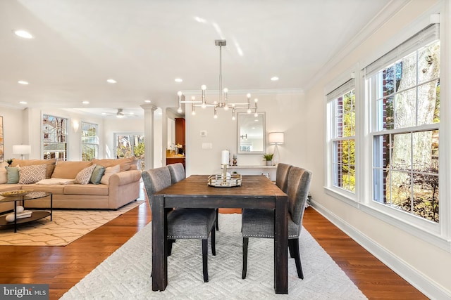 dining room featuring decorative columns, ornamental molding, a notable chandelier, and light hardwood / wood-style floors