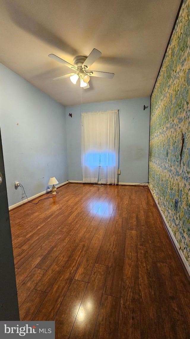 spare room featuring wallpapered walls, ceiling fan, wood finished floors, and baseboards