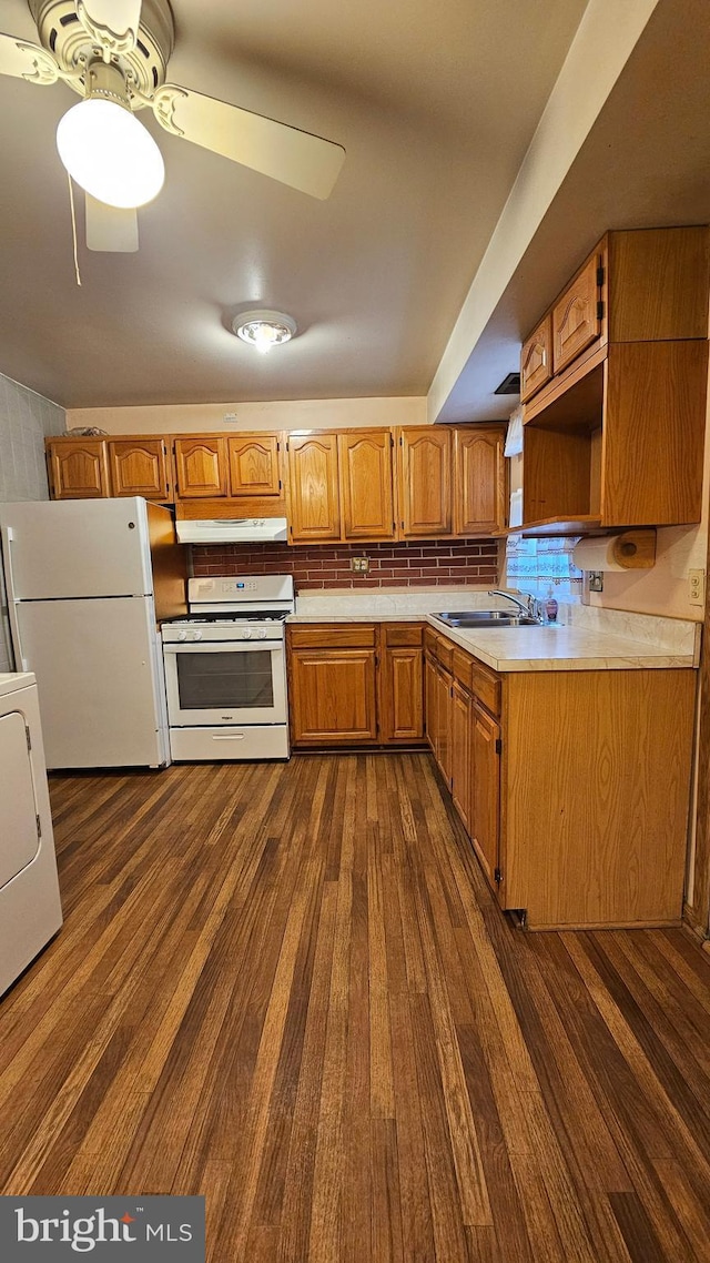 kitchen featuring under cabinet range hood, light countertops, washer / clothes dryer, white appliances, and dark wood-type flooring