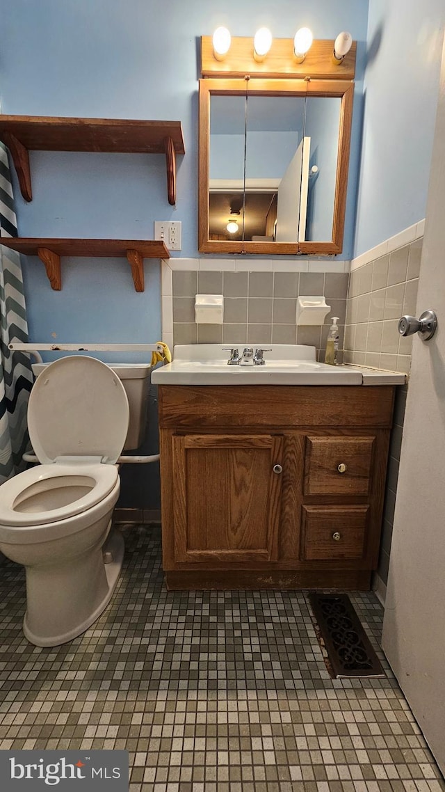 bathroom featuring toilet, tile walls, a wainscoted wall, and vanity